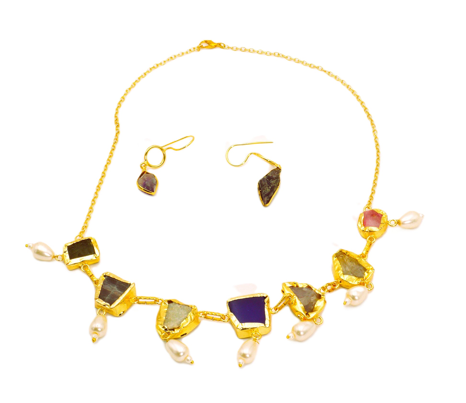 Gold necklace and earrings with gemstones on a white background
