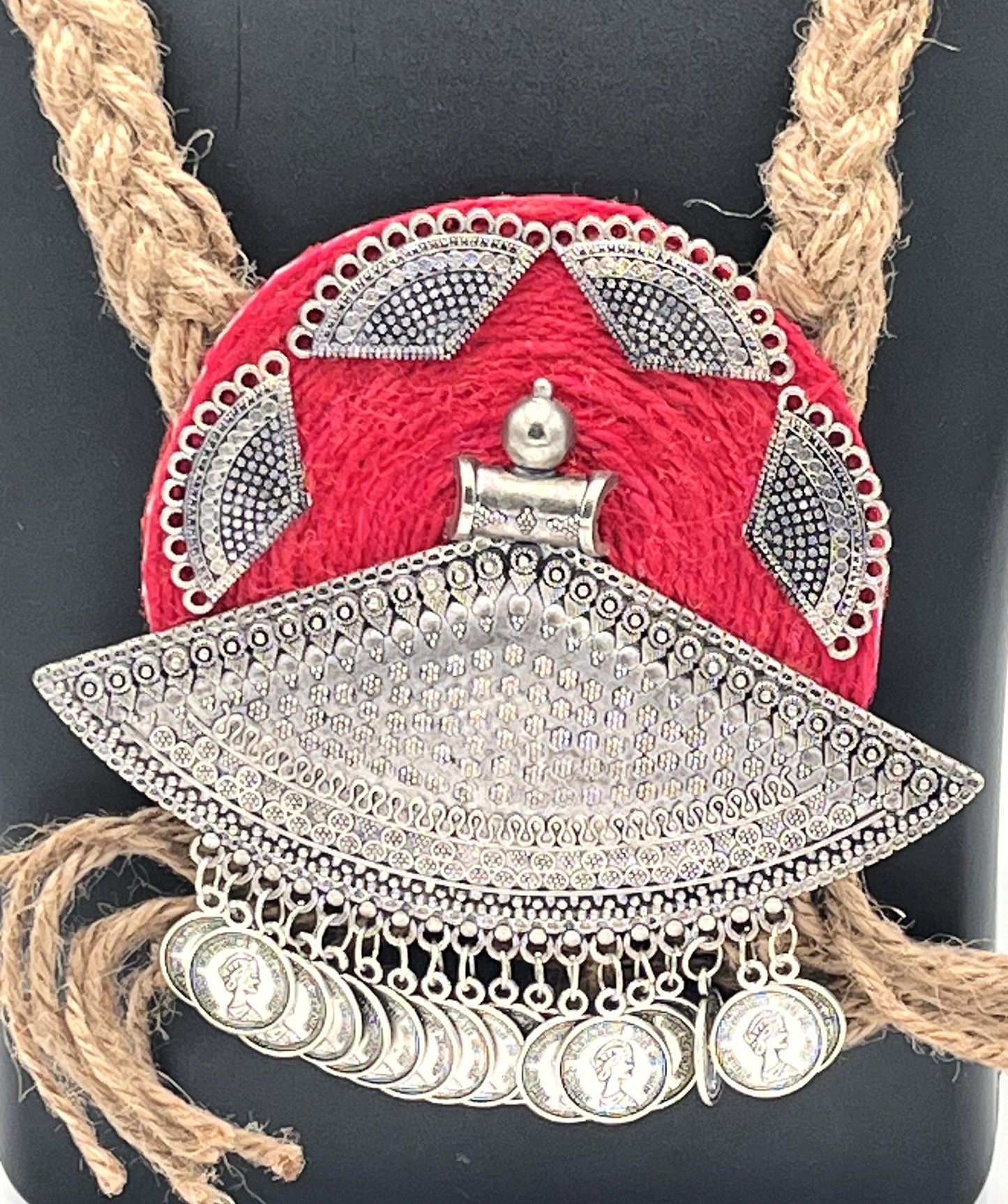 Close-up of oxidised silver coin pendant with red base – The Chakmak